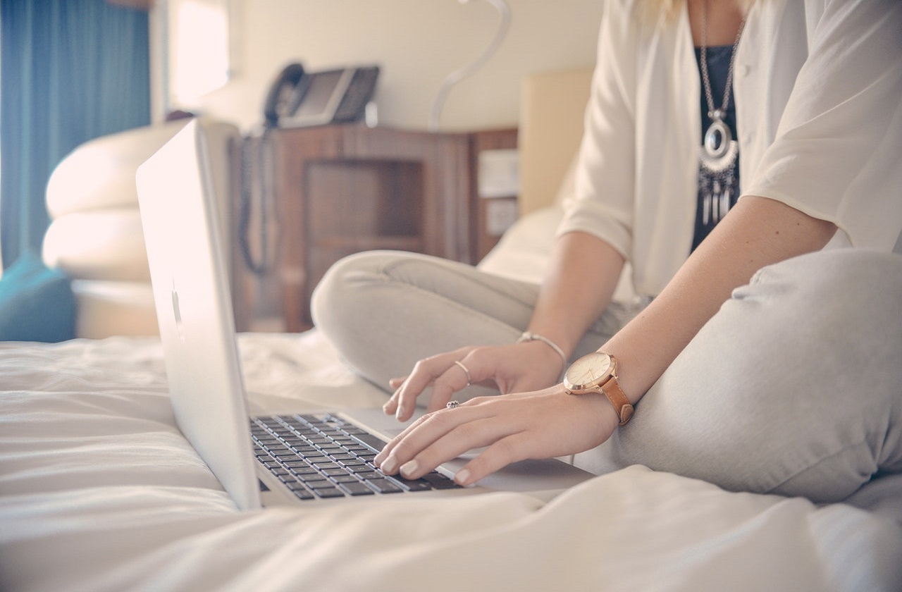 Woman sitting on bed using her laptop